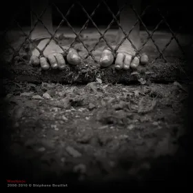 Pieds nus derrière une grille