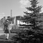 Marie Poppet devant la centrale de Tchernobyl Sa cheminée avait été détruite mais a été reconstruite. Le sarcophage avait été construit pour durer 30 ans, soit de 1986 à